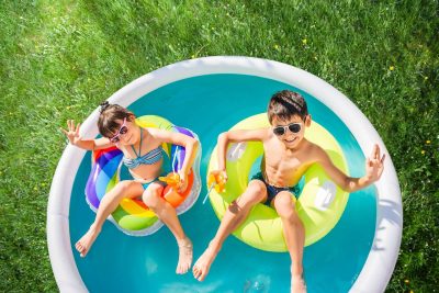 Children swim on inflatable circles in the blue water pool and drink orange juice