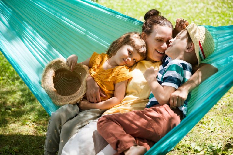 Mom and Two kids swing in a hammock in a summer park or garden